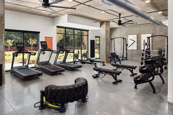 a gym with treadmills and other exercise equipment in a building with windows